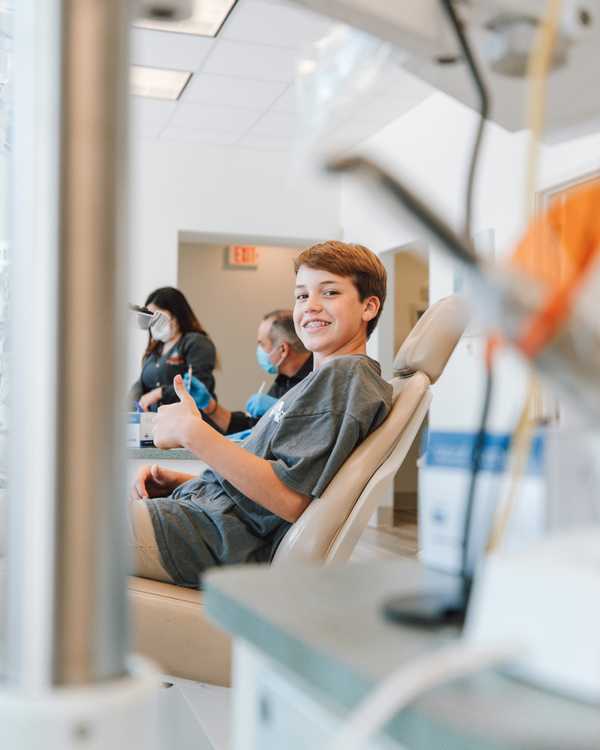 Young patient giving a thumbs up from the dental treatment chair