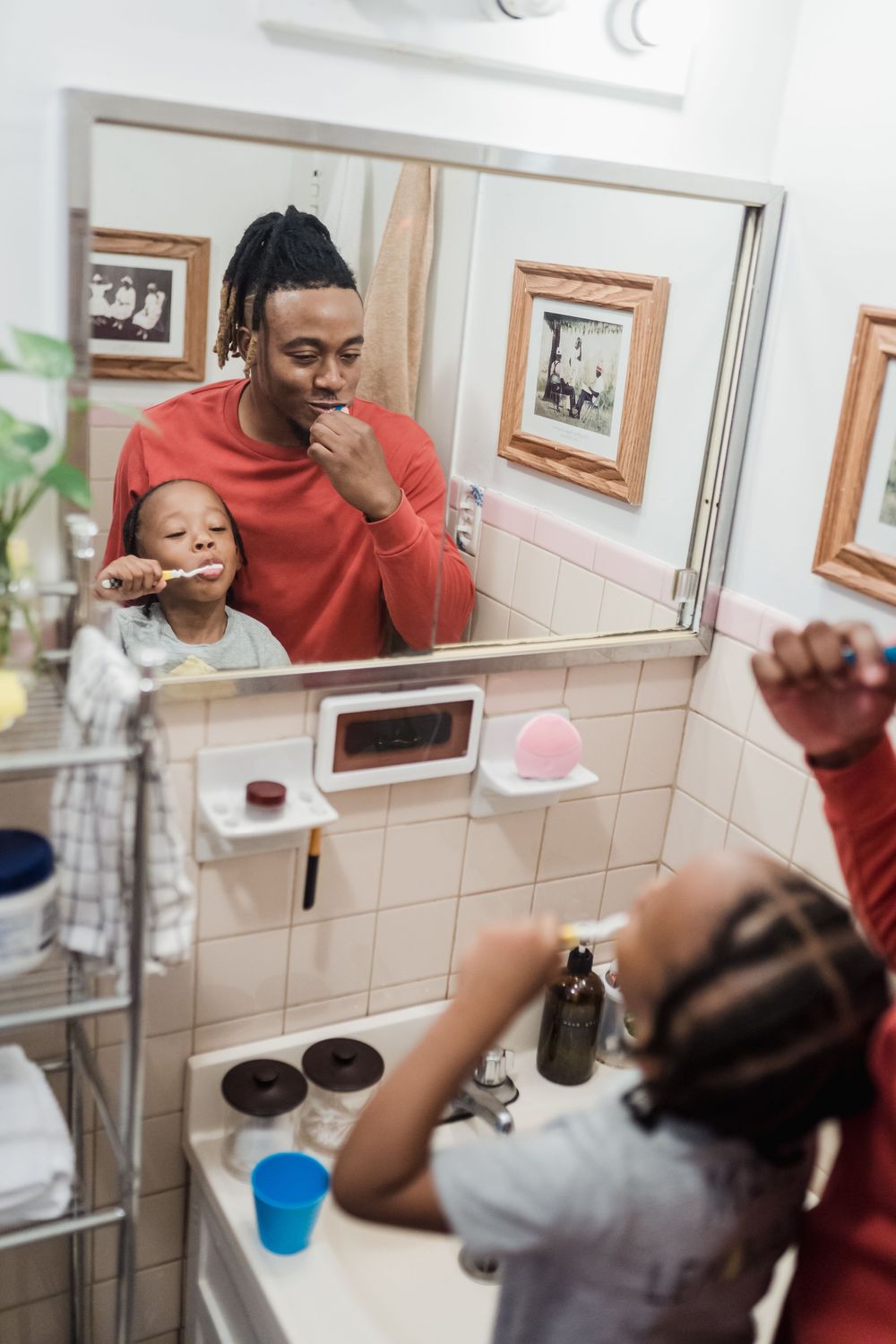 A father and his young son brushing their teeth together
